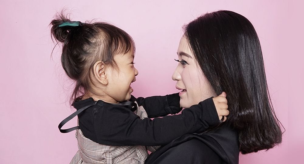 Mother and daughter in front of pink wall