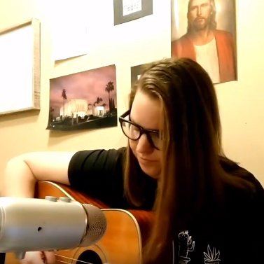 Rachel Gunderson playing a guitar and singing.