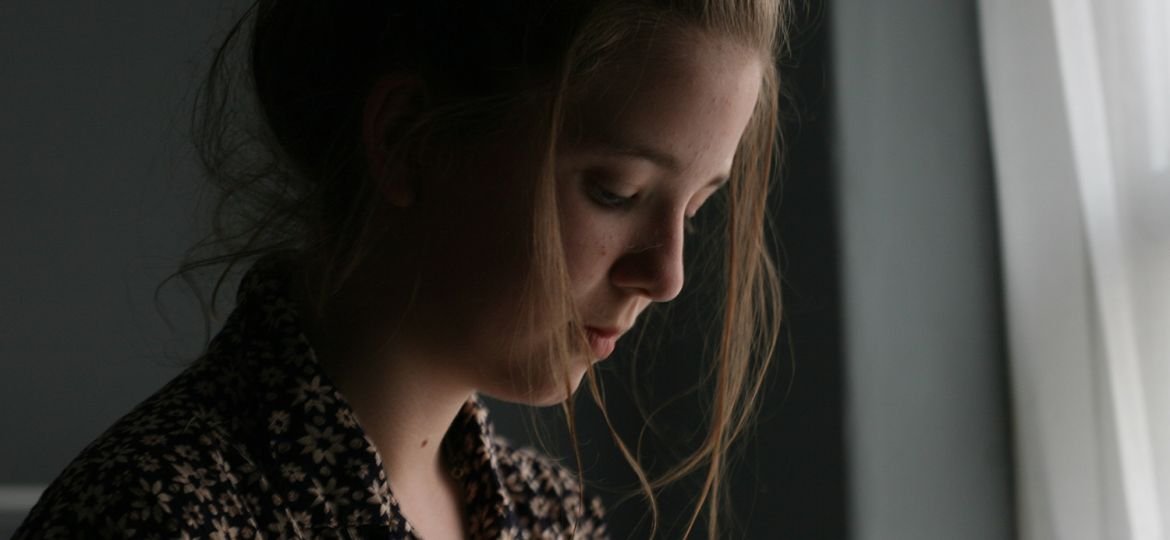 Sad woman standing next to window