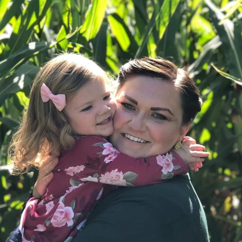 Woman and young girl smiling and hugging each other