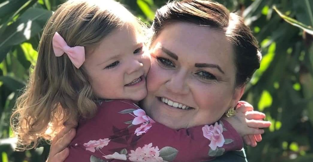 Woman and young girl smiling and hugging each other