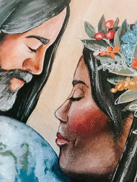 Man and woman of color wearing white clothing holding earth between them (detail of the man)