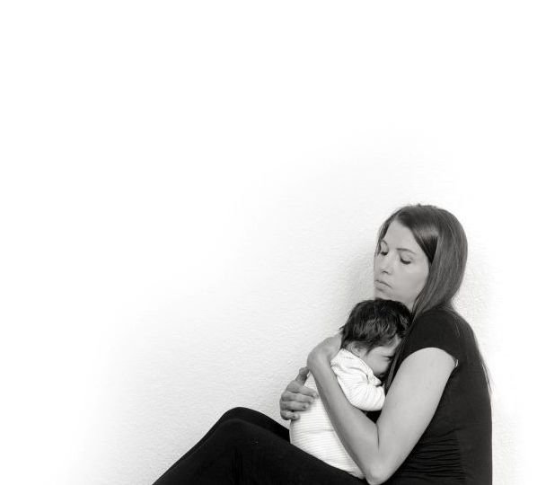 Woman sitting on floor holding dark haired baby