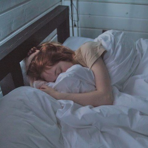 Woman sleeping in bed with white sheets and pillows
