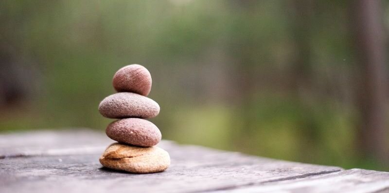 Four pebbles stacked on table outdoors