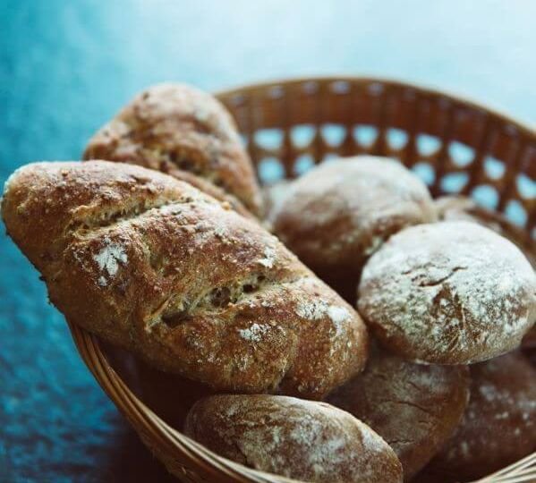 Hand-shaped bread in basket on blue tablecloth.