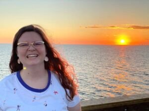 Matilyn Mortensen standing in front of water and sunset.