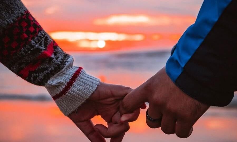 holding hands in front of a sunset